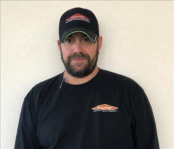 Male employee wearing a hat standing in front of a white background