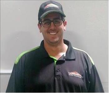 male employee wearing a hat smiling in front of a white background