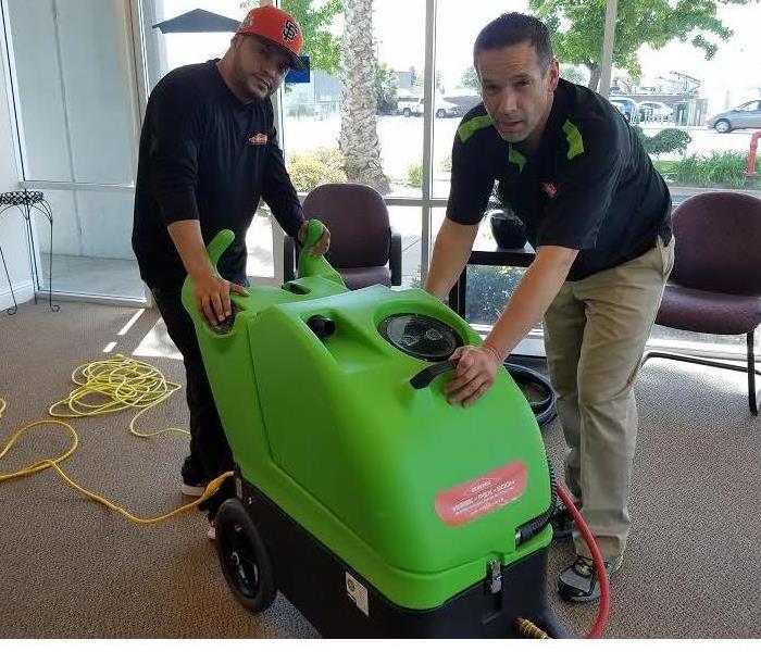 two male employees with a carpet cleaning machine